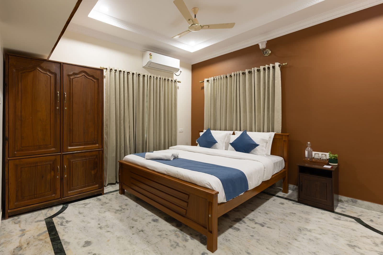 Room 1: a king bed against a terracotta wall, with a wooden wardrobe beside it