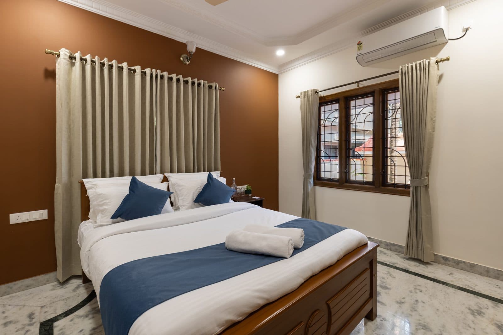 Room 2: a queen bed against a terracotta wall, with the window on the right