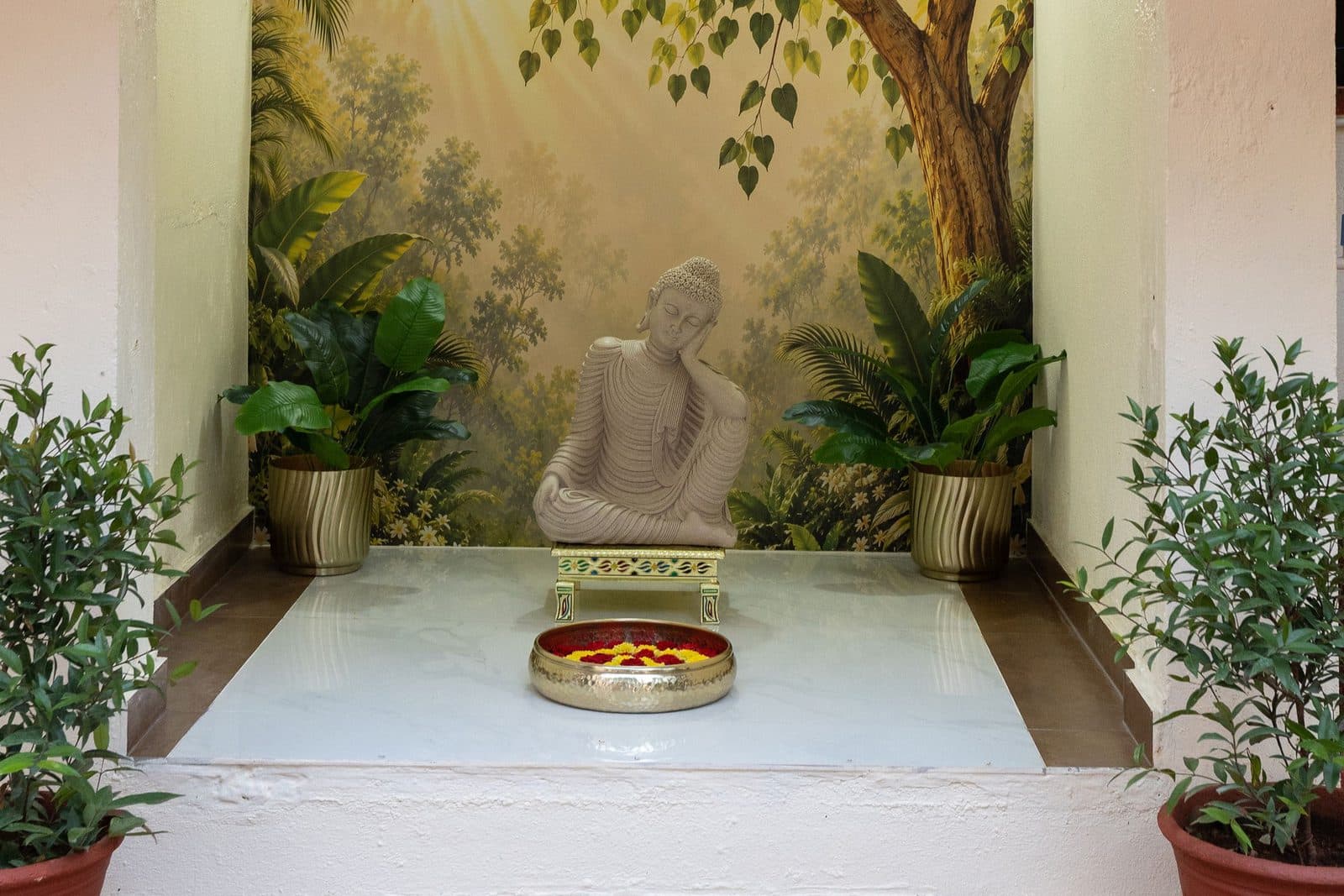 A corner of the entrance area with a seated Buddha, a painted wall and potted plants