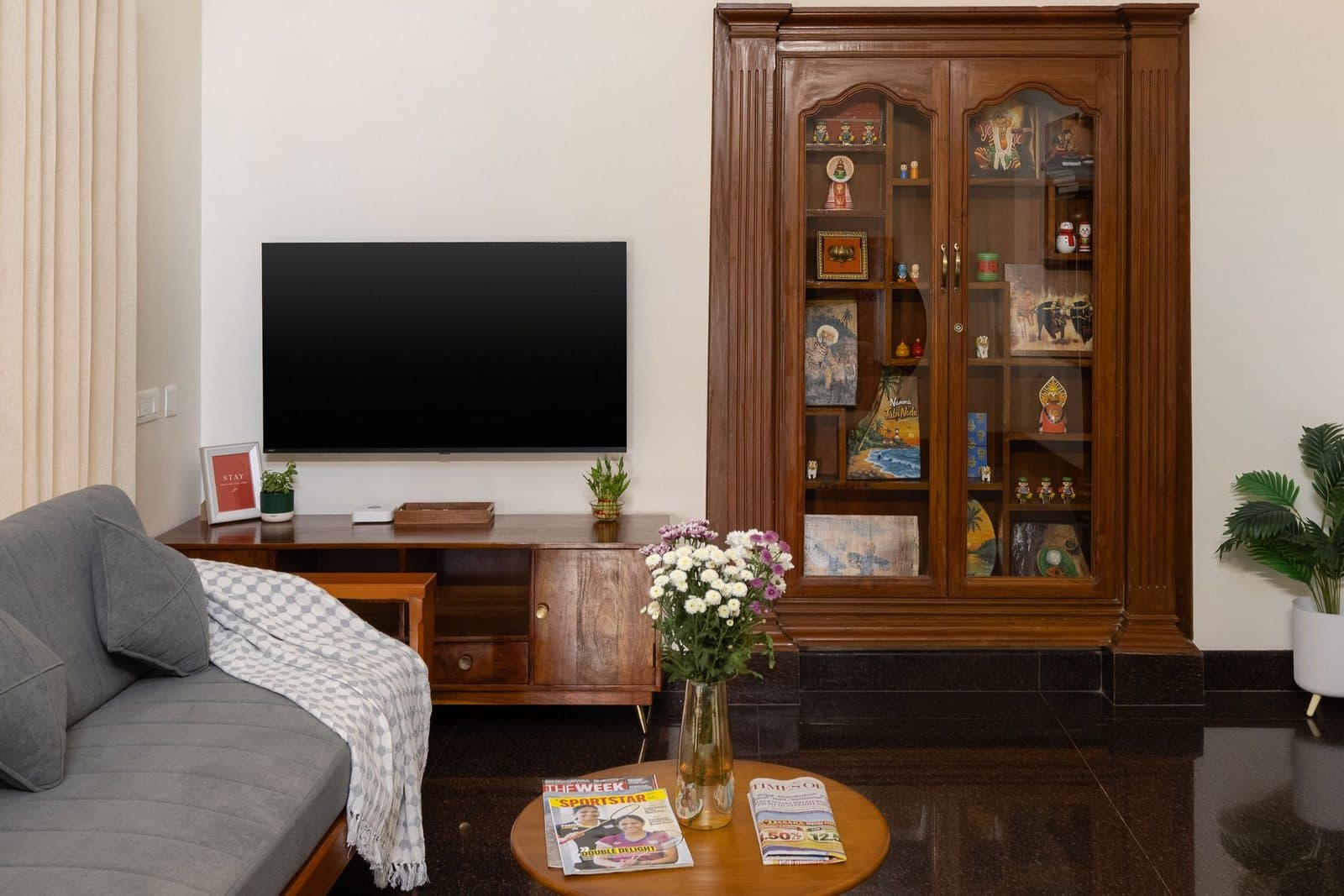 The living room, with a sofa, a television and a glass display cabinet against the wall