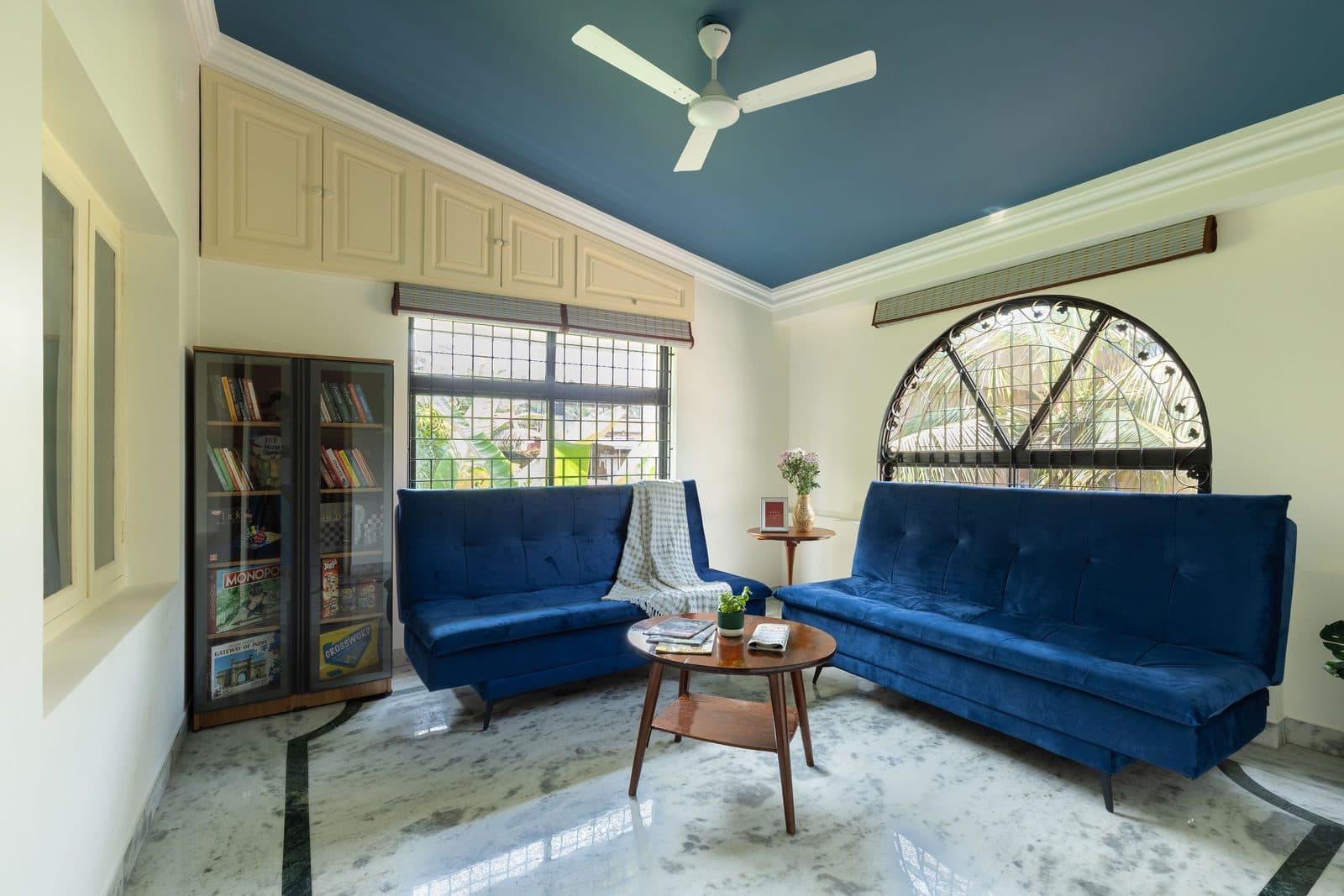 The private lounge, with two blue sofa-cum-beds, a bookcase and an arched window