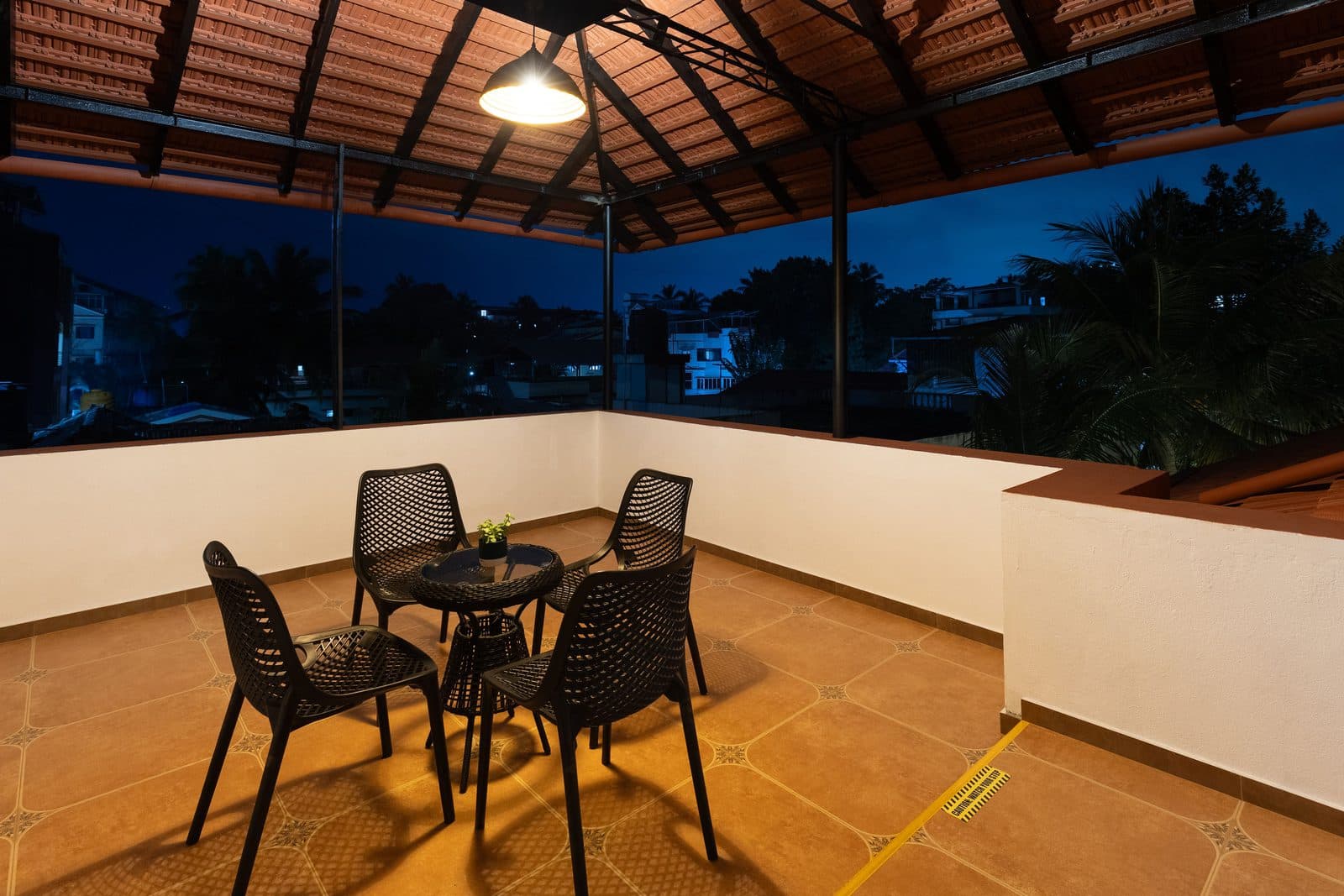 The second-floor sit-out at dusk, with a table and four chairs under the tiled roof