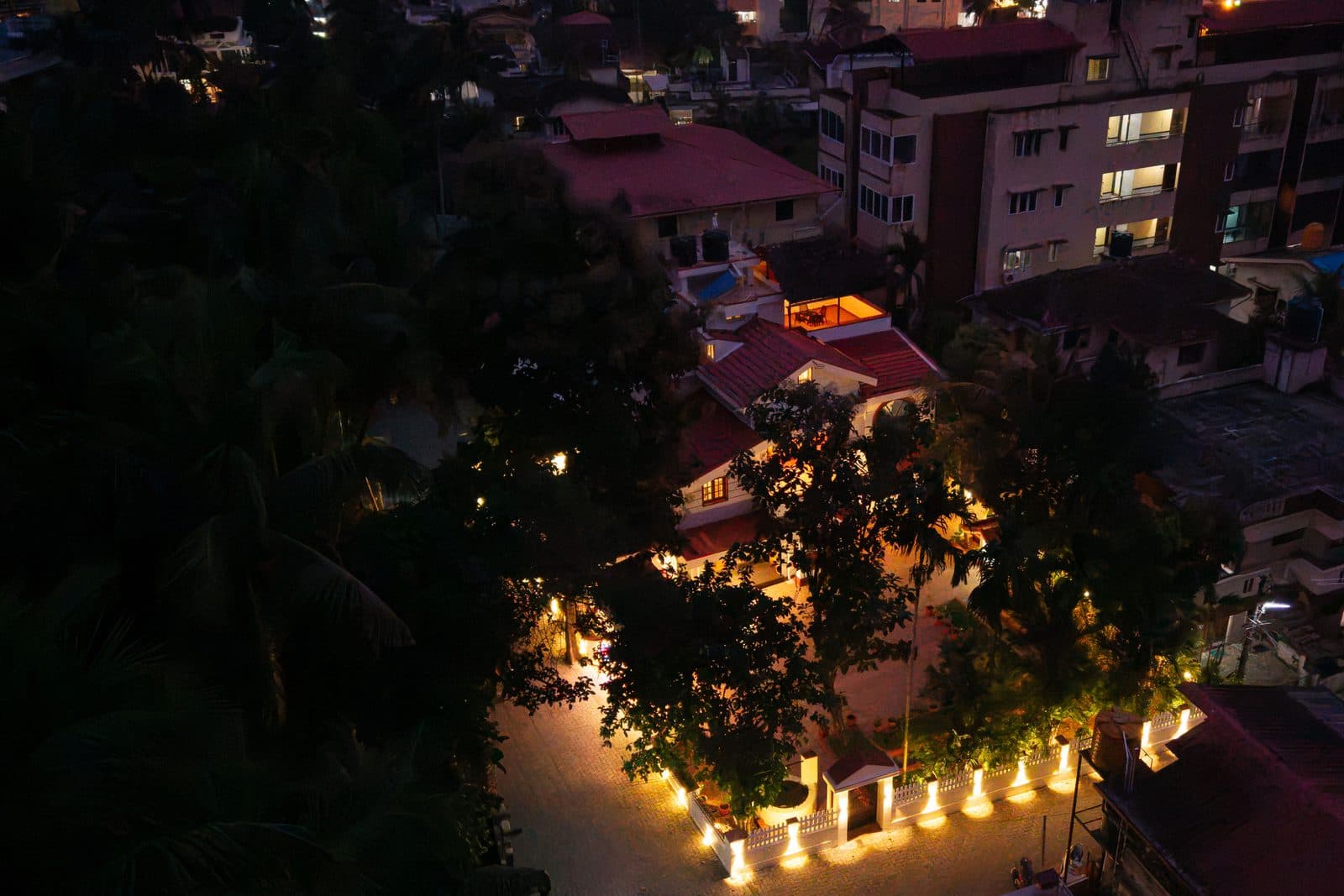 The compound from above at night, with the lit boundary wall and the trees over the front yard