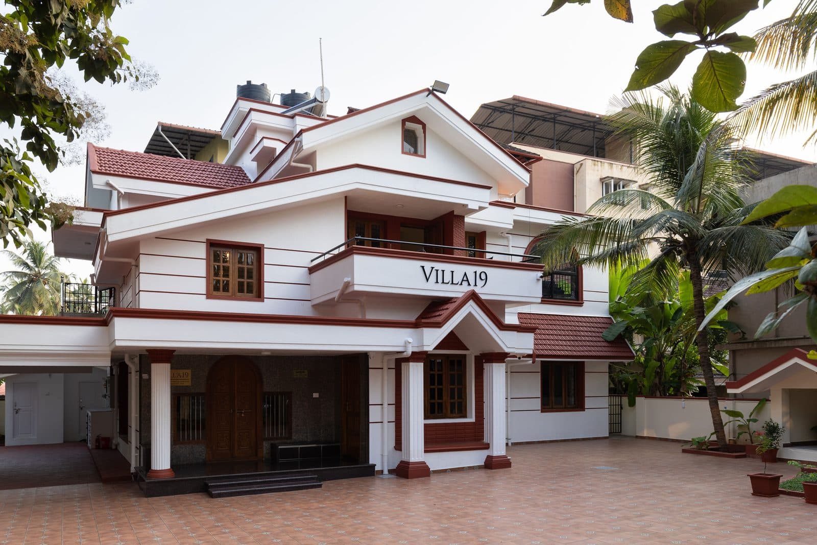 The villa from the side of the front yard, showing the porch, the tiled roof and the balcony